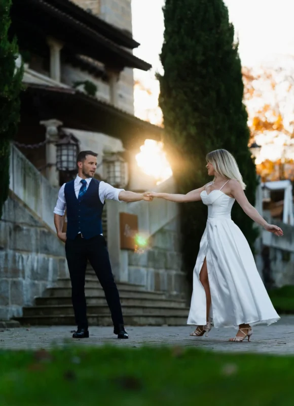 Bailes de boda al atardecer frente a una finca de piedra, con el sol detrás