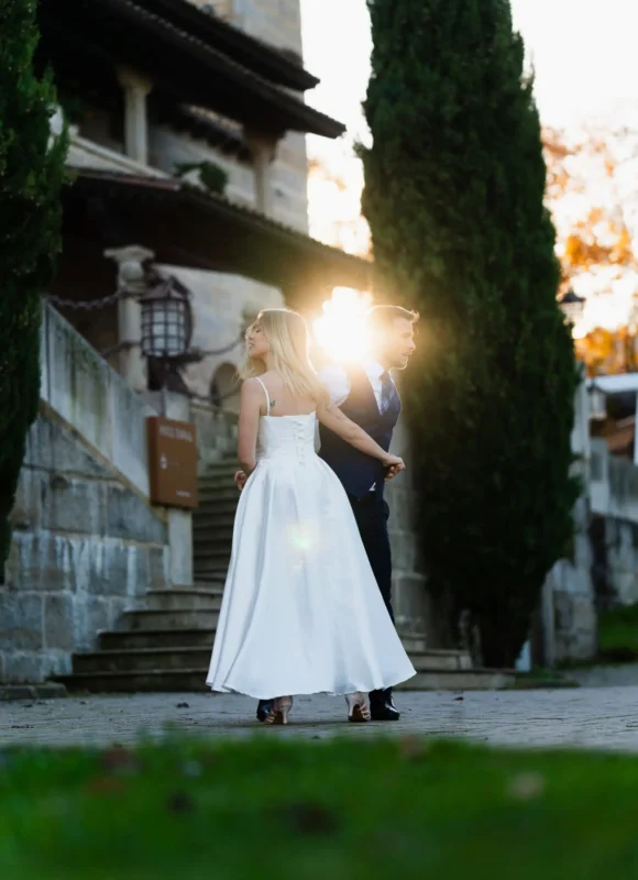 Novios en su baile de boda, con el sol de fondo y una finca de piedra