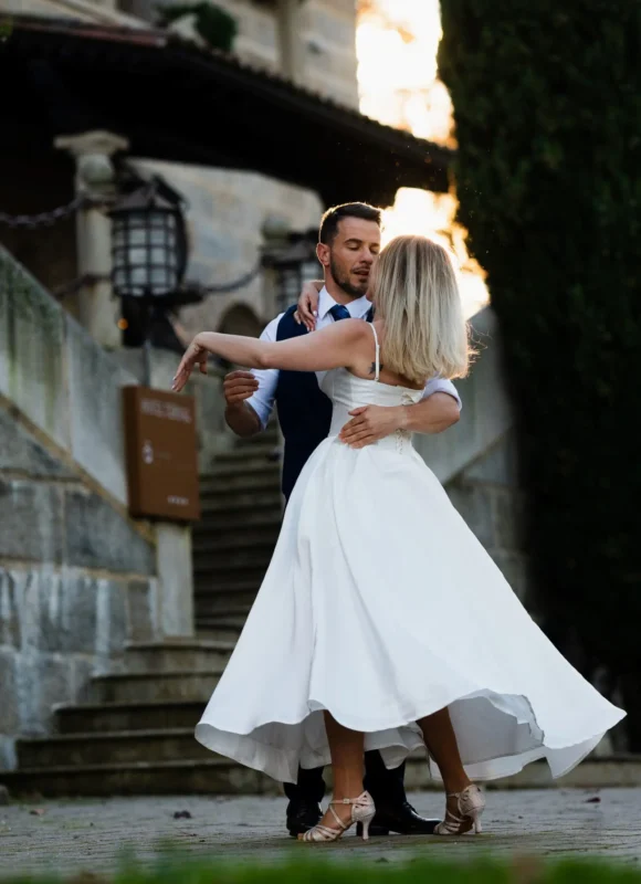 Novios bailando al aire libre con el vestido de la novia en movimiento.