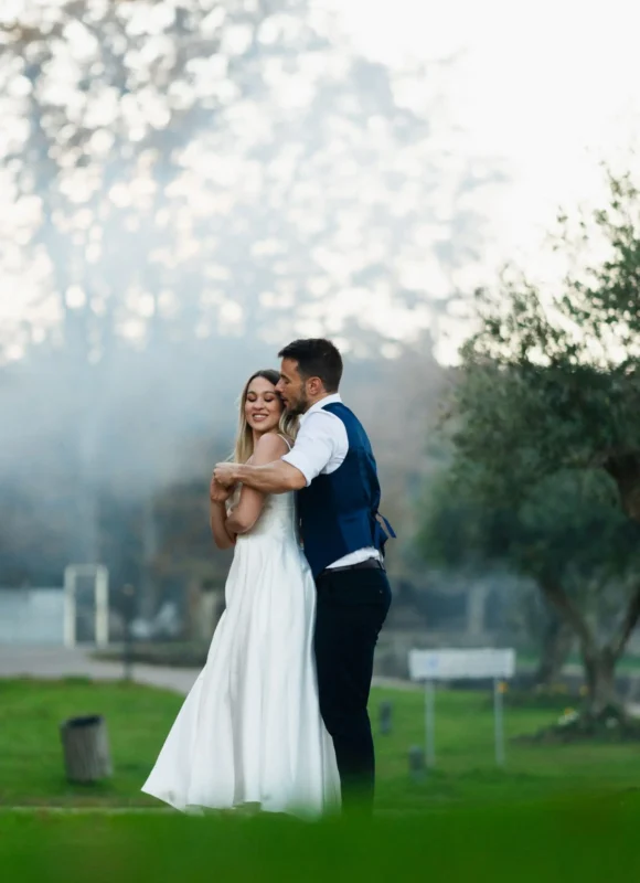 Novio abrazando por detrás a la novia mientras giran suavemente en sus bailes de boda al aire libre.