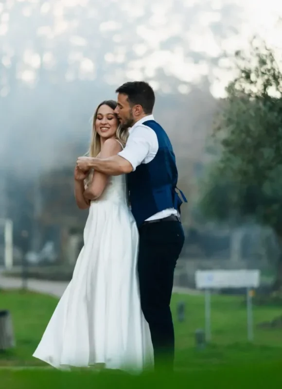 Novio abrazando por detrás a la novia mientras giran suavemente en sus bailes de boda al aire libre.