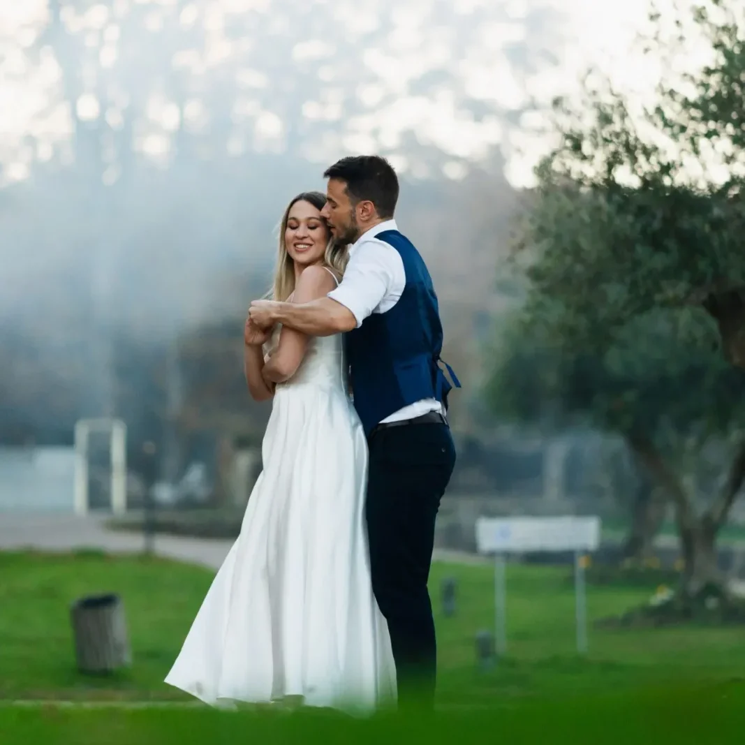 Novio abrazando por detrás a la novia mientras giran suavemente en sus bailes de boda al aire libre.