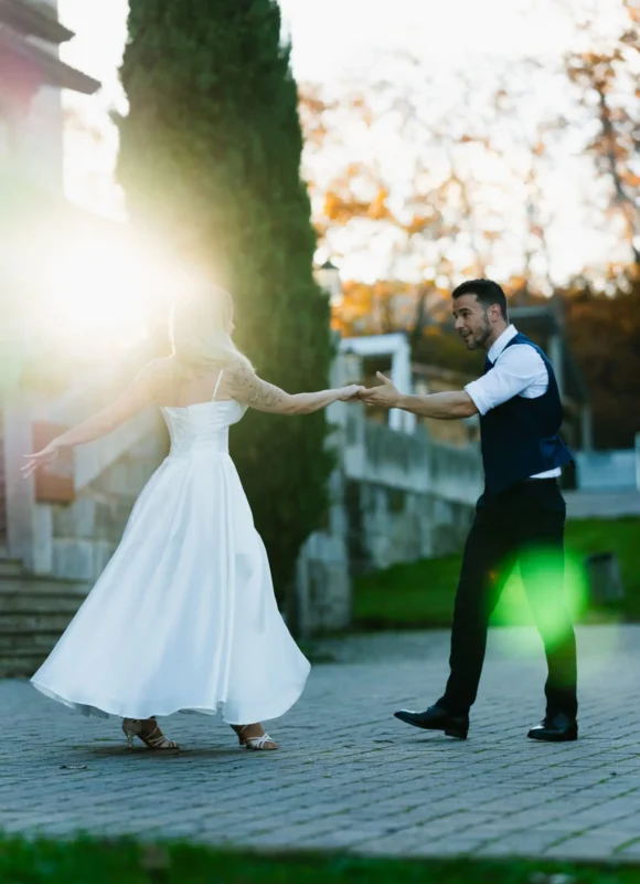 Baile de boda al atardecer, con destellos de luz y un jardín de fondo.